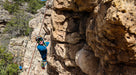 Person rock climbing on a rocky cliff face with ropes and climbing gear.