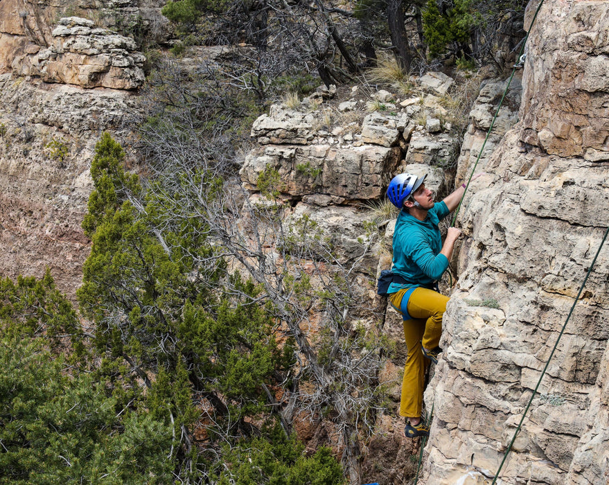 Person climbing a rocky cliff with safety gear