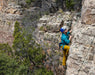 Person climbing a rocky cliff with safety gear