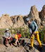 Three climbers on a rocky mountain ledge with a scenic background.