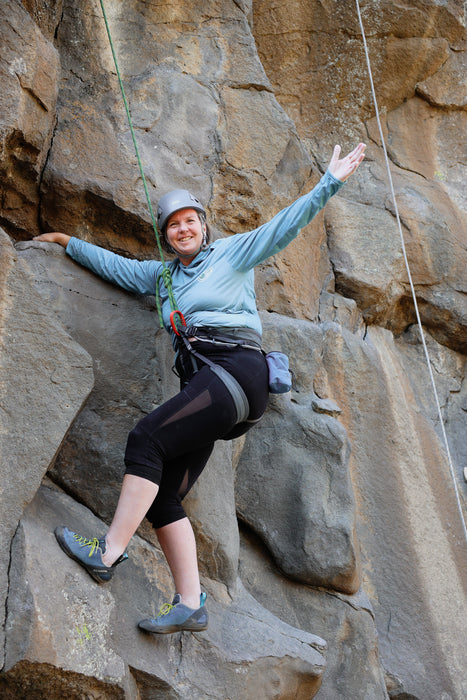 Person climbing a rocky cliff with safety gear
