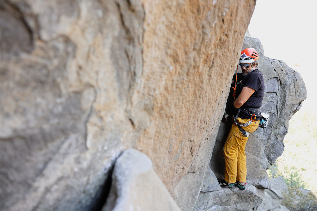 Person climbing a rocky cliff wearing safety gear