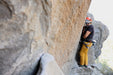 Person climbing a rocky cliff wearing safety gear