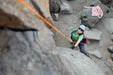 Person rock climbing on a rocky surface with ropes and equipment.