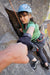 Person climbing a rock face with another person's hand reaching out to fist bump.