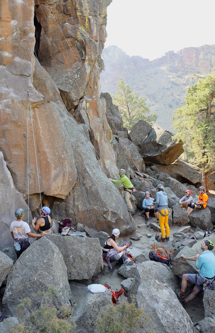 Group of people climbing and exploring rocky cliffs with a scenic background.