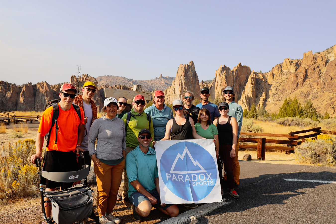 Group of people posing with a Paradox Sports sign in a desert landscape.