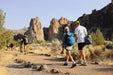 Hikers with backpacks walking on a trail with rocky formations in the background