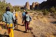 Group of hikers on a trail with rocky formations in the background.