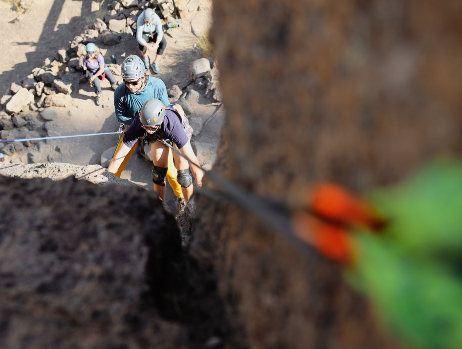 People climbing a rocky cliff with safety gear