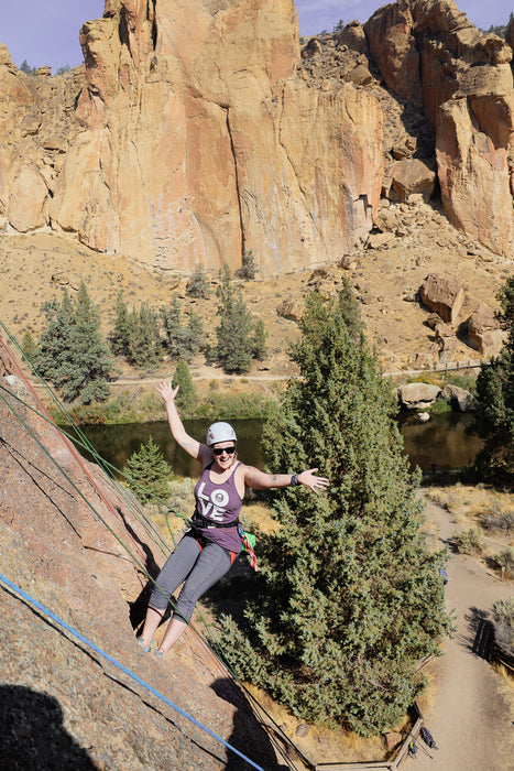 Person slacklining on a wooden platform with rock formations and trees in the background.