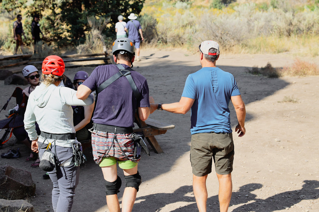 Group of people on a hiking trail with one person wearing a helmet and safety gear.