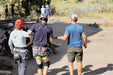 Group of people on a hiking trail with one person wearing a helmet and safety gear.