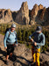 Two climbers on a rocky outcrop with mountainous landscape in the background.