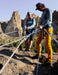 Two climbers on a rocky ledge with a scenic mountain background.