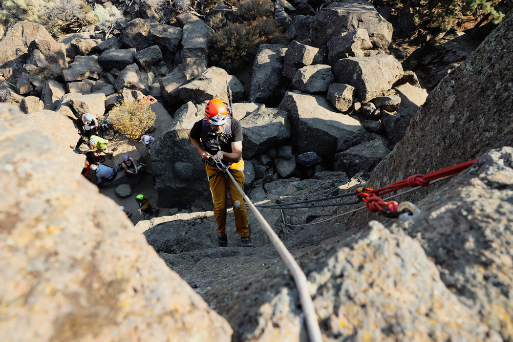 Person climbing a rocky cliff with ropes and equipment.