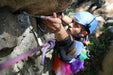 Person rock climbing with a blue helmet and colorful clothing.