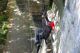 Person on a pulling themselves up a cliff from a rope system.