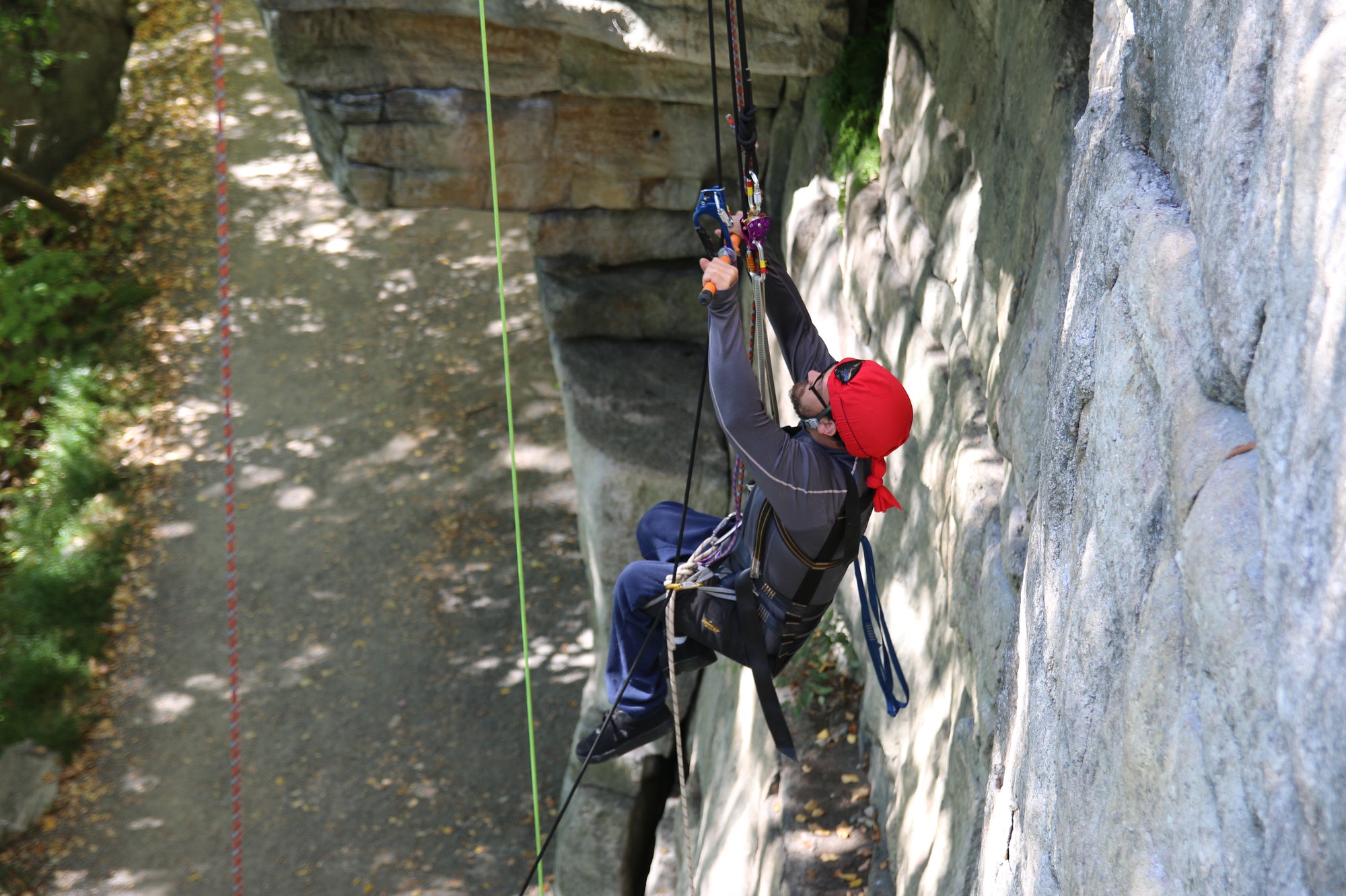 Person on a pulling themselves up a cliff from a rope system.