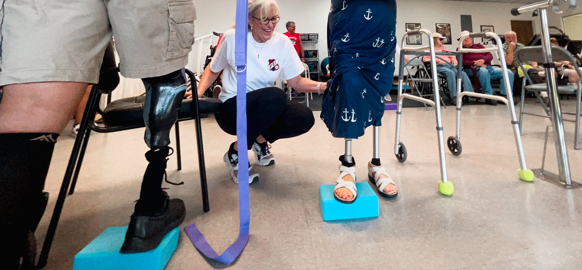 Susan Stenman of Prosthetic Solutions helping two patients practice standing on a block with their prosthetics at their Fitness For Life Clinics.