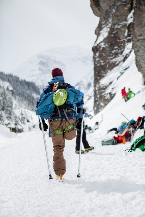 Person with a right above knee amputation standing with forearm crutches with ice climbing gear on