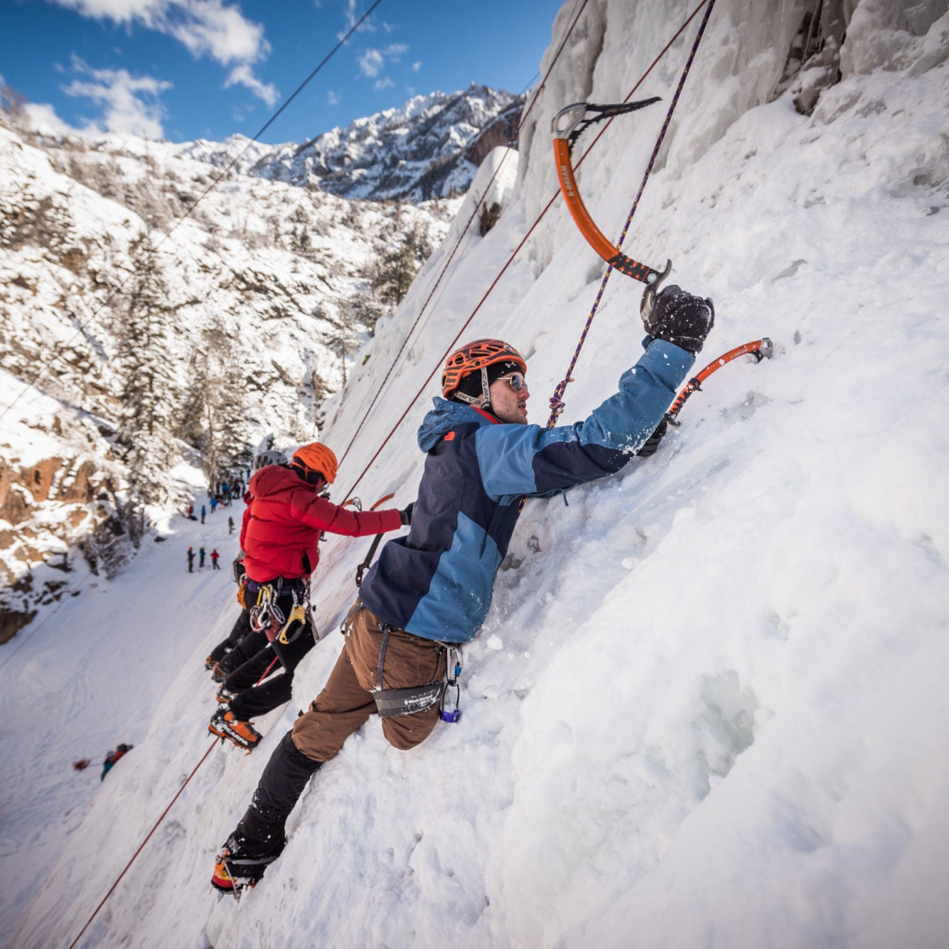 A Paradox Sports climber about to put their ice pick into the icewall with a group of Paradox Sports climbers next to them at the Ouray Ice Trip.