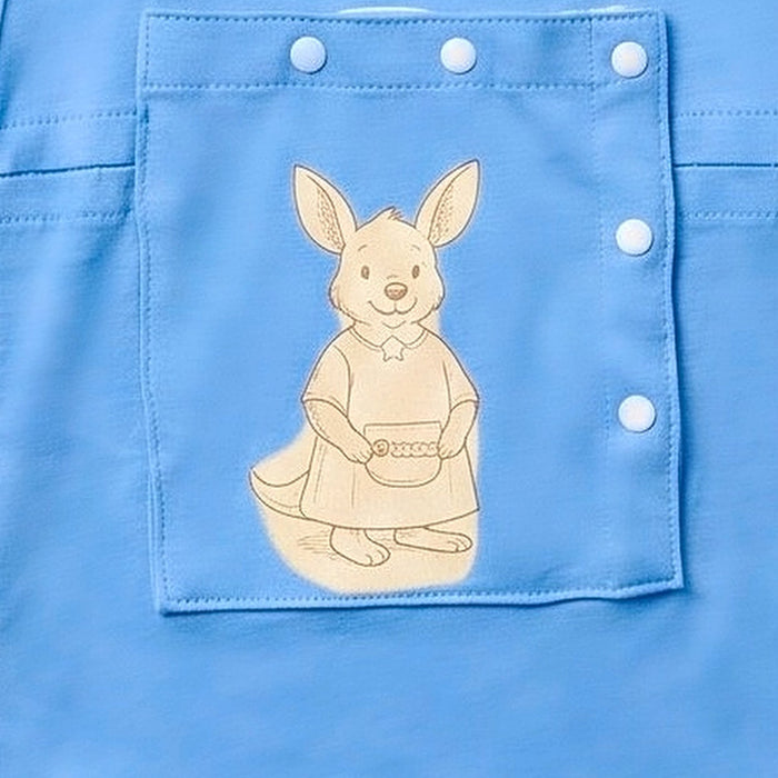 Close-up of the snap-closed chest pocket on the PediaTech Apparel LineWear Central Line Access Baby Gown in light blue (Sky Lullaby Edition), printed with an illustrated kangaroo in a dress holding a basket