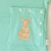 Close-up of the snap-closed pocket over the abdomen on the PediaTech Apparel TubeWear G/J Tube Access Baby Gown in mint green (Calm Mint Edition), printed with an illustrated kangaroo in a dress holding a basket