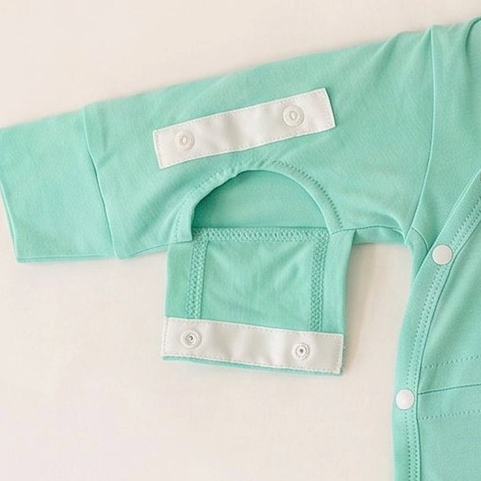 Close-up of a sleeve on the PediaTech Apparel TubeWear G/J Tube Access Baby Gown in mint green (Calm Mint Edition) with the arm-access opening along the inner seam unsnapped and its flap folded down