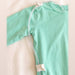 Close-up of clear tubing threaded through the white guides at the shoulder and lower back of the PediaTech Apparel TubeWear G/J Tube Access Baby Gown in mint green (Calm Mint Edition)