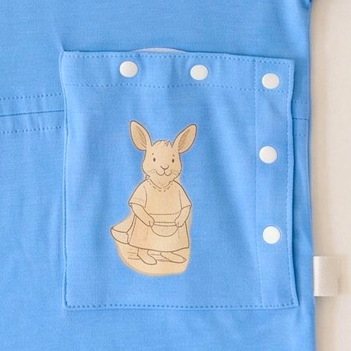 Close-up of the snap-closed pocket over the abdomen on the PediaTech Apparel TubeWear G/J Tube Access Baby Gown in light blue (Sky Lullaby Edition), printed with an illustrated kangaroo in a dress holding a basket