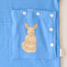 Close-up of the snap-closed pocket over the abdomen on the PediaTech Apparel TubeWear G/J Tube Access Baby Gown in light blue (Sky Lullaby Edition), printed with an illustrated kangaroo in a dress holding a basket