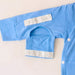 Close-up of a sleeve on the PediaTech Apparel TubeWear G/J Tube Access Baby Gown in light blue (Sky Lullaby Edition) with the arm-access opening along the inner seam unsnapped and its flap folded down