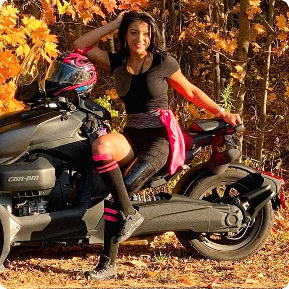 Portrait of Team Amplife® Ambassador Rouzalin Hakim sitting on the side of her 3 wheel Can-Am motorcycle in the autumn woods