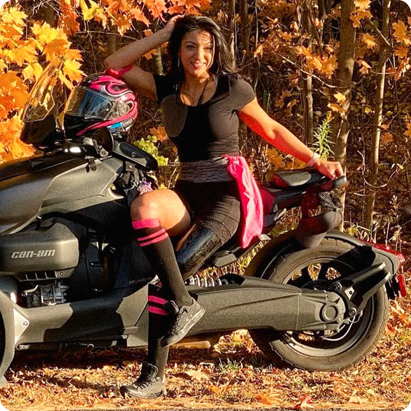 Portrait of Team Amplife® Ambassador Rouzalin Hakim sitting on the side of her 3 wheel Can-Am motorcycle in the autumn woods