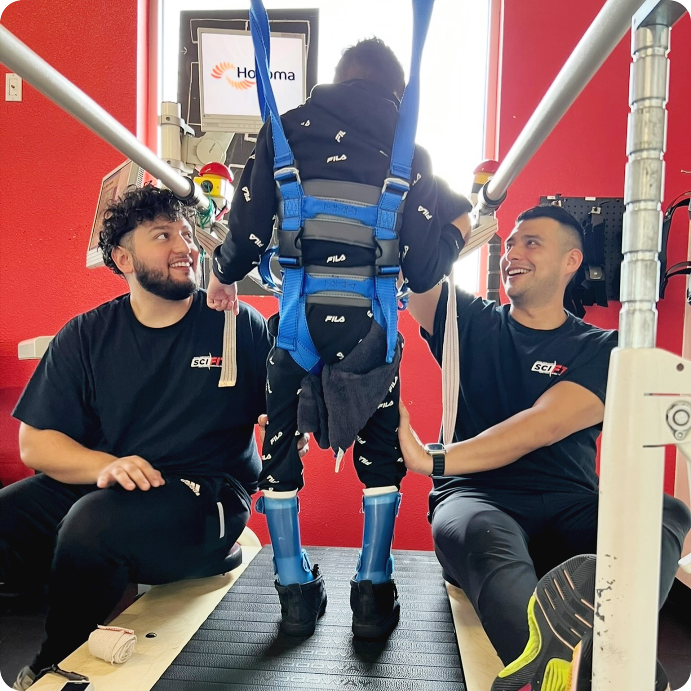 Person walking with a harness with assistance from two individuals from SCI-FIT