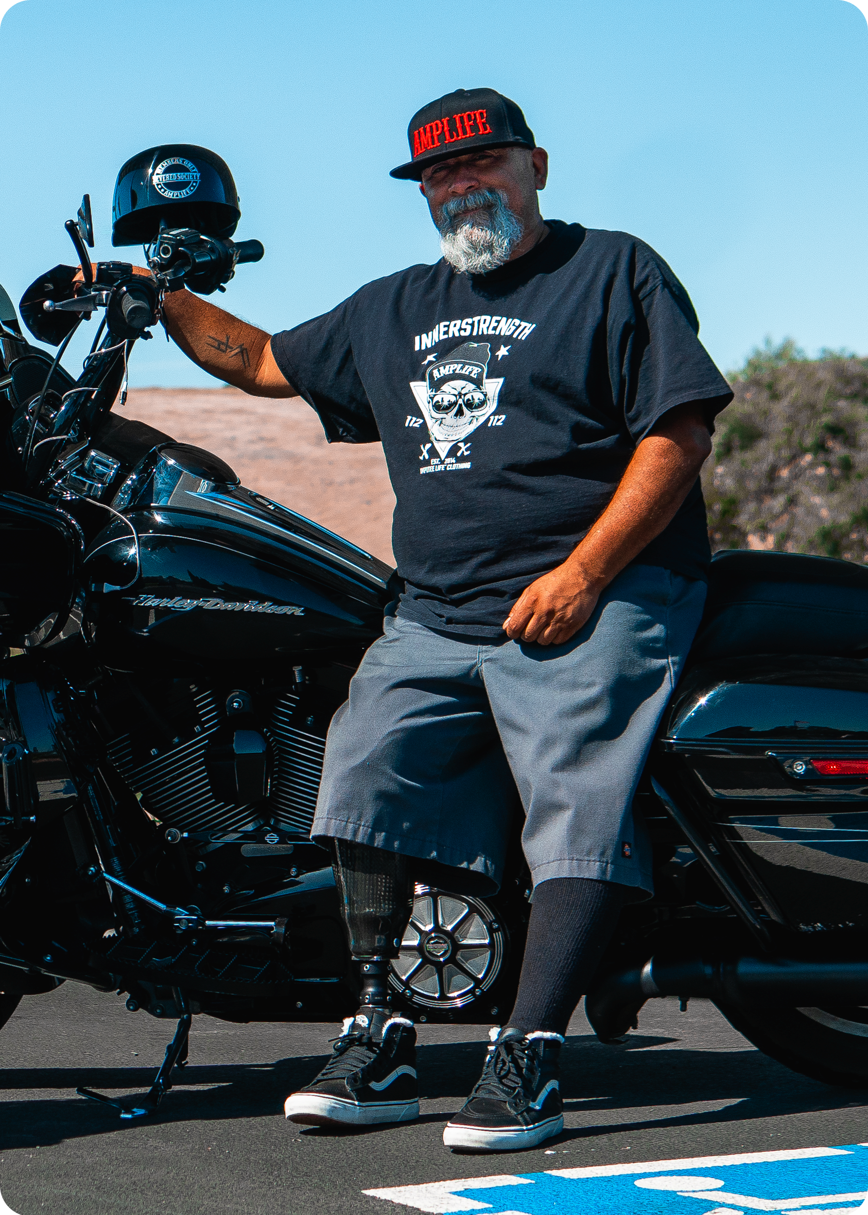 Team Amplife® Ambassador Steven Hill wearing the Amplife® Flat Bill Fitted & Amplife® Innerstrength T-Shirt standing next to his motorcycle.