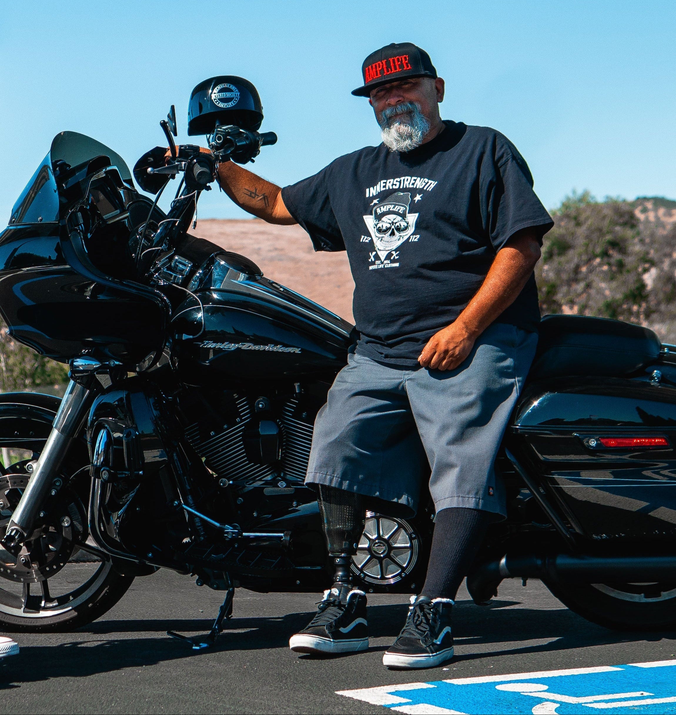 Team Amplife® Ambassador Steven Hill wearing the Amplife® Flat Bill Fitted standing next to his motorcycle.