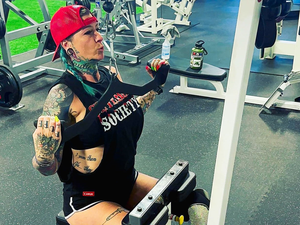 SuZanne Jacobsen performing a lat pulldown while wearing the Severed Society® Drip T-Shirt.