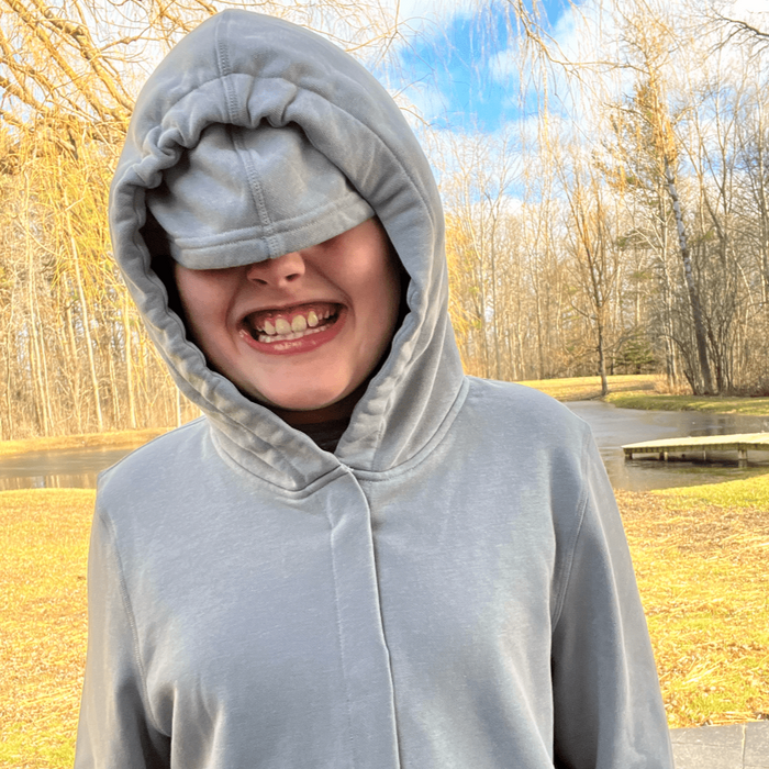 Person wearing a Sense-ational You QuietSense Sound Reducing Sensory Grey Hoodie outdoors with trees and sky in the background