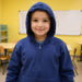 Child wearing a Child wearing a Sense-ational You QuietSense Sound Reducing Sensory Youth Zippered Hoodie on a white background in a classroom setting