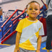 Child wearing a Sense-ational You Sensory Friendly Yellow/Mint Youth T-Shirt in an indoor playground setting