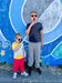 Two children posing in front of a colorful mural with sunglasses while wearing Sense-ational You Sensory Friendly Youth T-Shirts