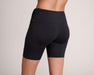 Back angle of a model wearing Slick Chicks Adaptive Athletic Biker Shorts, against a beige background