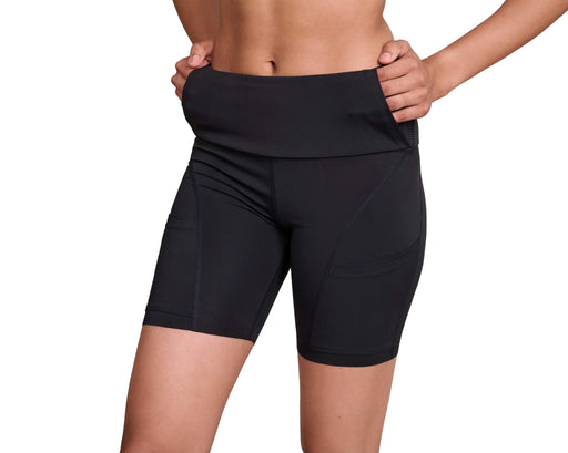 Close up of a model wearing Slick Chicks Adaptive Athletic Biker Shorts, demonstrating the pull-up pockets with their fingers inside pulling up, against a white background