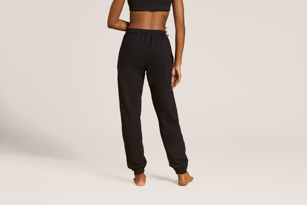 Back angle of a model wearing Slick Chicks Adaptive Fitted Lounge Joggers in black against a beige background