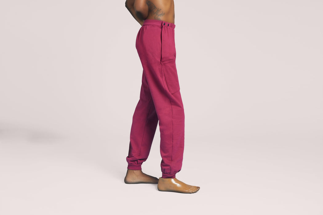 Side angle of a model wearing Slick Chicks Adaptive Fitted Lounge Joggers in plum against a beige background