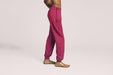 Side angle of a model wearing Slick Chicks Adaptive Fitted Lounge Joggers in plum against a beige background