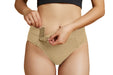 Close-up of a model wearing Slick Chicks Adaptive High Waist Panty in beige, pulling open the VELCRO Brand Fasteners with two hands against a plain white background