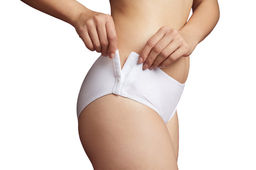 Close-up of a model wearing Slick Chicks Adaptive Hipster Panty in white, pulling the hook & eye side closures with both hands against a plain white background